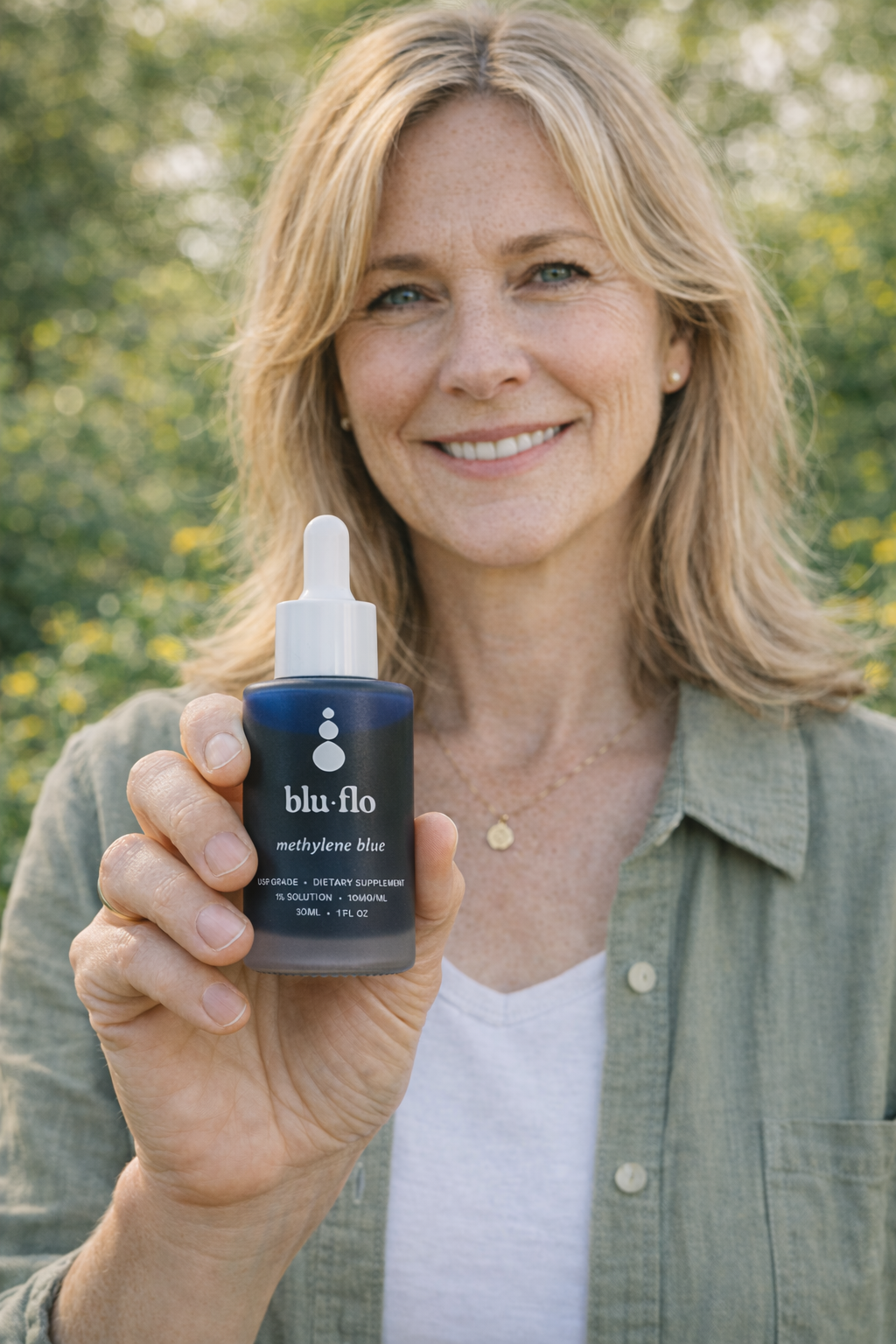 Woman holding a blu flor methylene blue bottle against a natural background
