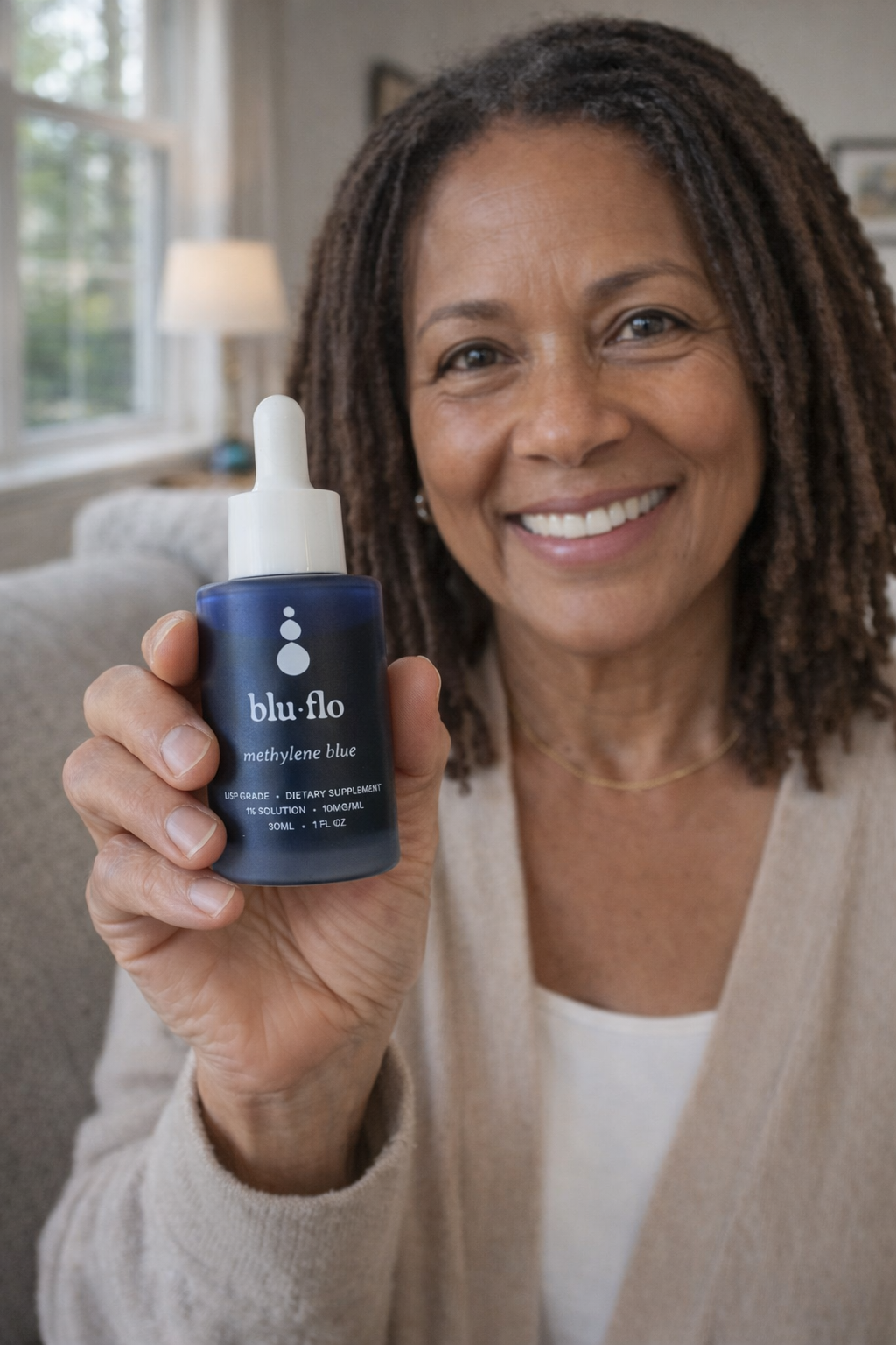 Woman holding a bottle of blu flo methylene blue in a home setting