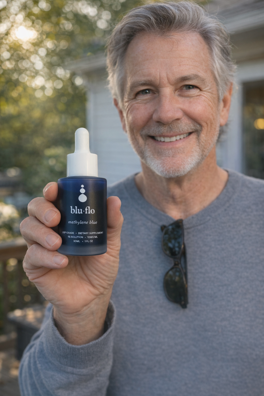 Man holding a methylene blue bottle labeled 'blu flo' outdoors